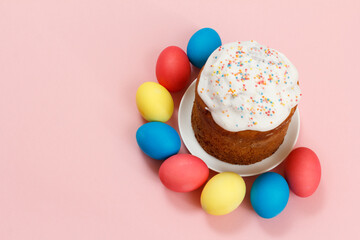 Easter cake on a plate and colored eggs with pink background.