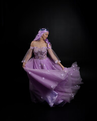Full length portrait of girl wearing long purple fantasy ball gown with crown and pink hair,...