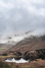 Beautiful landscape Winter sunrise of Blea Tarn from Side Pike in English Lake District with low level clouds over mountain tops