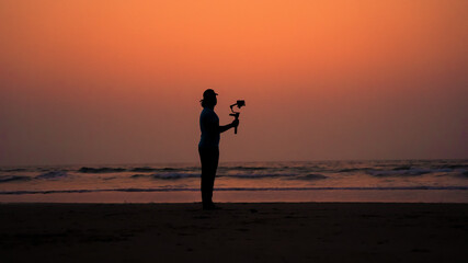 Fototapeta premium A filmmaker filming near beach silhouette