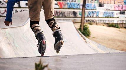 Roller skater jumping in a half pipe in an urban skate park