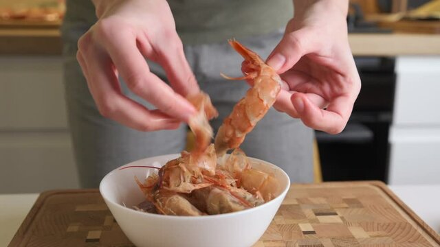 Woman cleaning shrimps for cooking. Process of hands peel shrimps shell