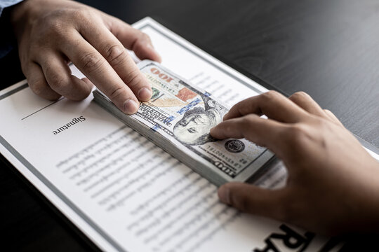 Business men are handing over large dollar bills to their business partners as money for bribery in order to cheat companies, corruption is illegal and immoral. The concept of corruption.
