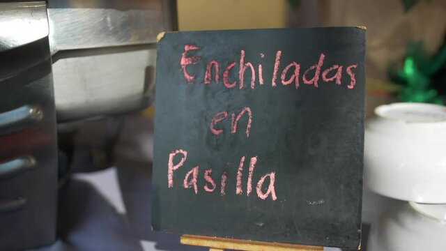 Metal pot and black sign with pink Spanish text on a table