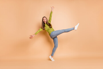 Fototapeta premium Full length photo of lady dance raise hands leg wear green pullover footwear jeans isolated beige color background