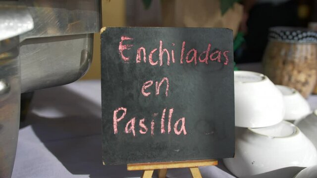 Metal pot and black sign with pink Spanish text on a table