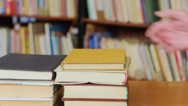A man's hands puts stacks of books on the table in library