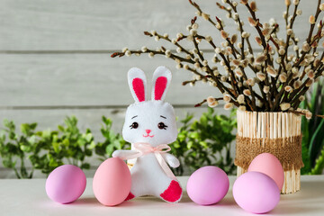 Easter composition with painted eggs, rabbit, willow twigs in a decorative pot