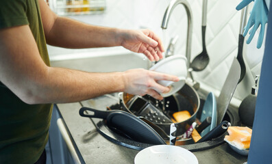 Young man washing dishes in the kitchen.