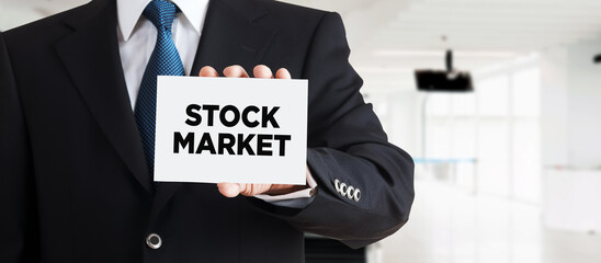 Businessman shows a business card with the word stock market. Business finance