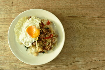 spicy stir fried chop pork with basil leaf on rice topping egg in plate