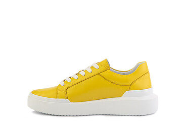 Bright yellow leather sneakers. Casual women's style. White lacing and white rubber soles. Isolated close-up on white background. Left side view. Fashion shoes.