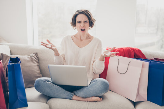 Full body photo of upset furious young woman sit couch unhappy shopping bags addicted indoors inside living-room
