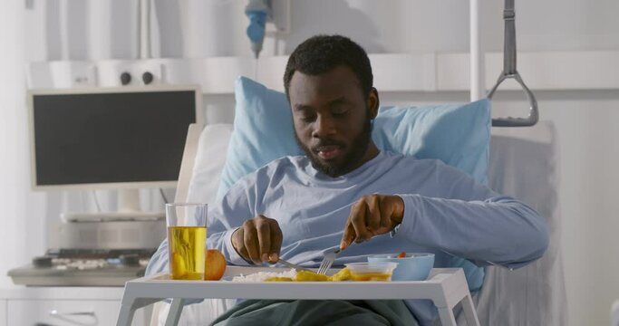 African young male patient eating food in hospital bed