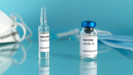 Covid-19 vaccination concept. The doctor's gloved hand puts vaccine vial and syringe on the table in the laboratory.