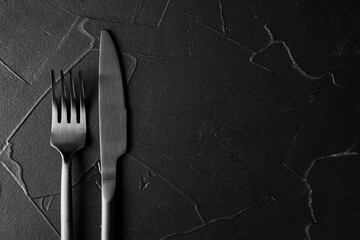 black textured background with black fork and knife - obrazy, fototapety, plakaty