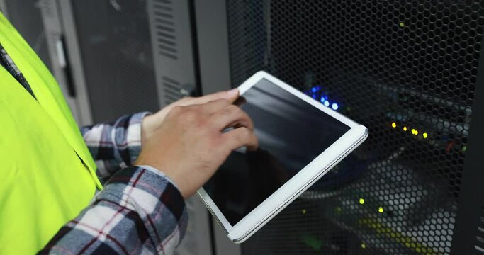 Technician man holding digital tablet while examining server in server room