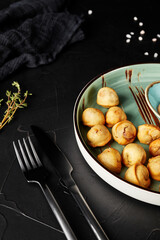 fried dumplings on a plate on a black textured background with a fork and knife