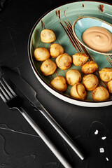 fried dumplings on a plate on a black textured background with a fork and knife