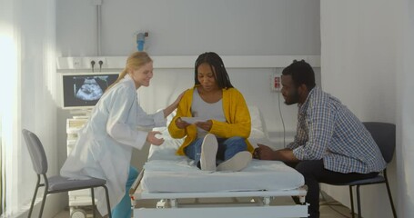 Happy african couple holding ultrasound image after examination in hospital