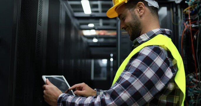 Technician man holding digital tablet while examining server in server room
