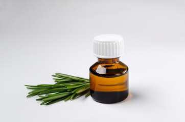 Closeup of brown glass bottle of rosemary oil on the white background