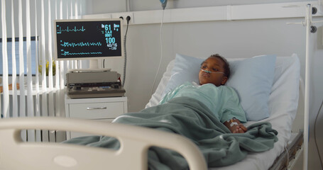 African kid with nasal oxygen tube lying in hospital bed