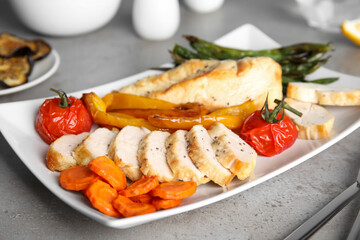 Tasty cooked chicken fillet and vegetables served on grey table. Healthy meals from air fryer