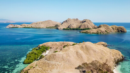 Fototapeta na wymiar A drone shot of two bigger paradise islands in Komodo National Park, Flores, Indonesia. The islands have scarcely any trees and bushes. Dry land. Idyllic white sand beaches. Island hoping