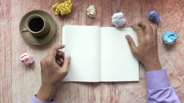 crumpled paper ball and notepad on wooden table.