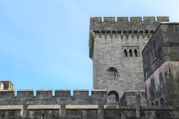 Crenellated walls and tower on a fairy tale castle made of stone blocks.