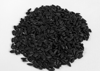 Black sunflower seeds scattered in a bunch on a white background.