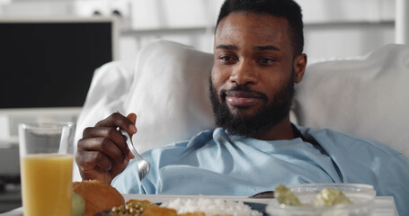 Portrait of afro-american man eating healthy meal in hospital room.