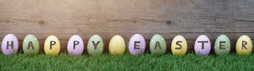 HAPPY EASTER background banner panorama greeting card - Many pastel painted dotted Easter eggs on fresh green meadow grasses and rustic wooden wood wall