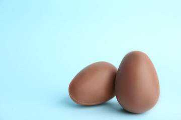Sweet chocolate eggs on light blue background. Space for text