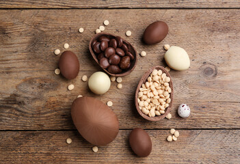 Sweet chocolate eggs and candies on wooden table, flat lay