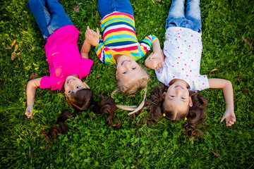 three little girls of Asian, Indian and European ethnic races lie on the gajon in the summer. International Children's Day