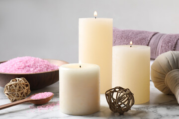 Aromatic candles and pink sea salt on white marble table
