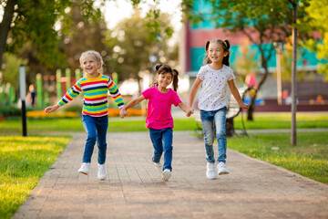 Fototapeta na wymiar three girls of Asian, European and Indian ethnicity run in summer in the park