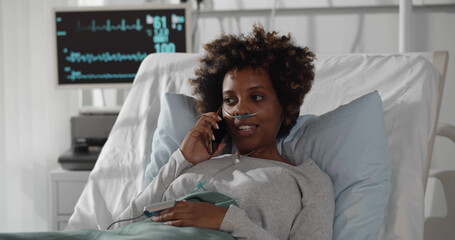 African lady patient having phone conversation in hospital room