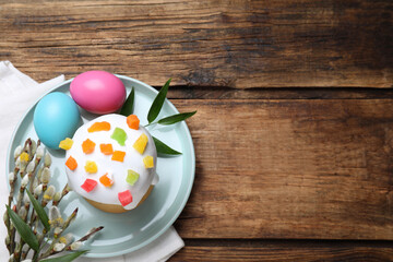 Easter cake and painted eggs on wooden table, flat lay. Space for text