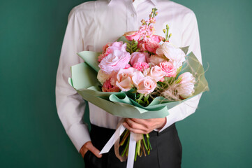 Man holding and giving a beautiful bouquet with flowers to woman on green background. Front view. Valentine's, women's, mother's day, love concept.