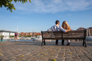 Couple on a bench - Two lovers sitting on a bench in a park and holding themselves by hands -...