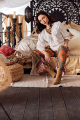 Mature beautiful dark haired woman in shamanic ethnic outfit in bali style decorated room