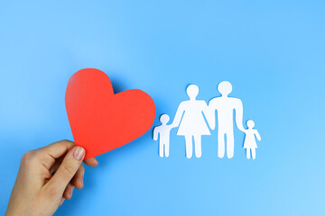 family cut out of paper and heart in hands. Love and family concept