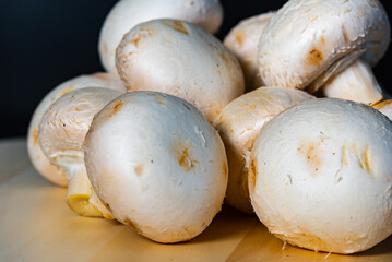 white mushrooms champignons lie on a wooden board