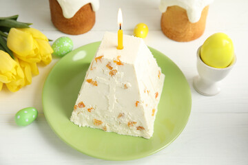 Traditional cottage cheese Easter paskha with dried apricot and burning candle on white wooden table
