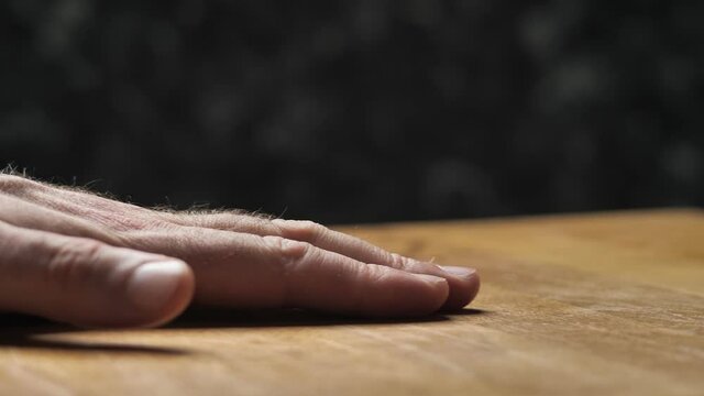 Male hand strokes a wooden oiled table top. Checking the quality of the work performed.