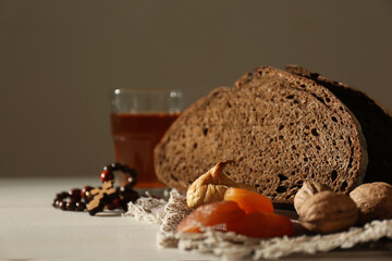 Rosary beads, dried fruits, walnuts, bread and drink on table. Lent season