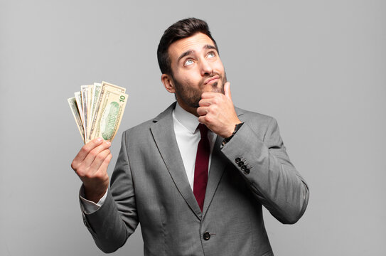 young handsome businessman thinking, feeling doubtful and confused, with different options, wondering which decision to make. bills or money concept - Powered by Adobe